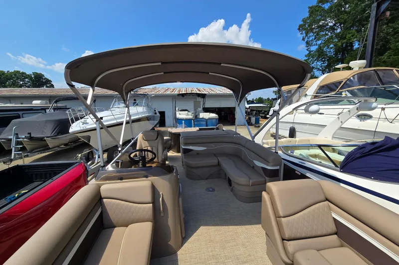 Slide: The Image of 2024 Bennington S22 pontoon boat with spacious seating and canopy, docked at a marina. - 13
