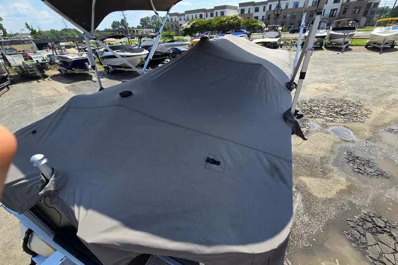 Slide: The Image of 2024 Bennington S22 pontoon boat covered, parked in a marina lot. - 12