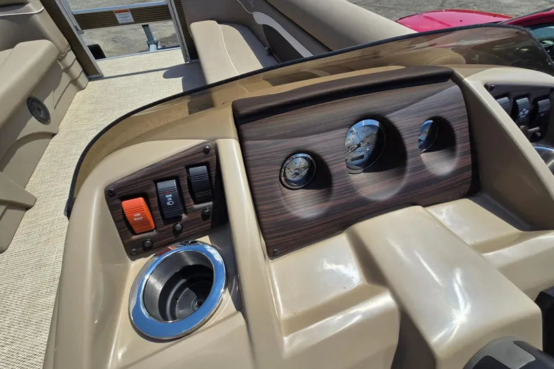 Slide: The Image of 2024 Bennington S22 dashboard with gauges, switches, and cup holder in a beige interior. - 25