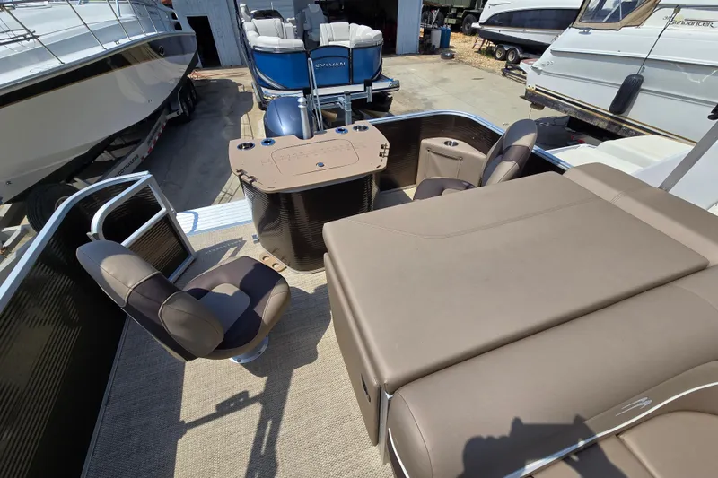 Slide: The Image of 2024 Bennington S22 pontoon boat interior with seating and table, docked among other boats. - 20