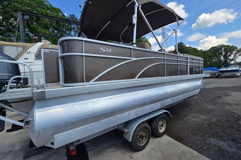Slide: The Image of 2024 Bennington S22 pontoon boat on trailer, parked outdoors under a blue sky. - 9