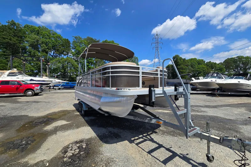 Slide: The Image of 2024 Bennington S22 pontoon boat on trailer in marina under blue sky. - 6