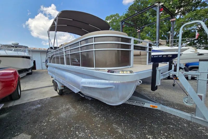 Slide: The Image of 2024 Bennington S22 pontoon boat on trailer, parked outdoors under a blue sky. - 10