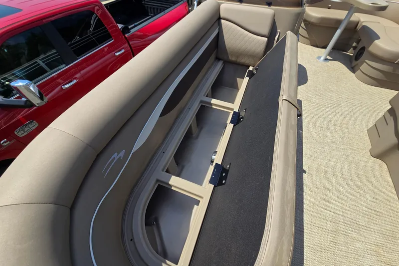 Slide: The Image of 2024 Bennington S22 boat interior with open storage compartment and beige seating. - 29