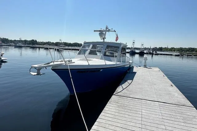 Slide: The Image of 1999 Michael Fitz Pilothouse boat docked on calm water under clear blue sky. - 1