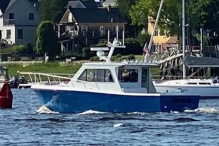 The Image of A 1999 Michael Fitz Pilothouse boat cruising on a scenic waterfront. - 0