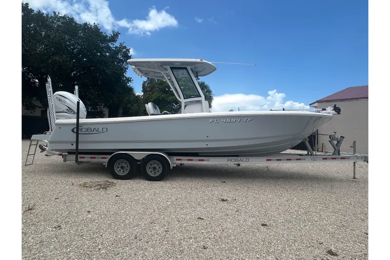 The Image of 2022 Robalo 266 Cayman boat on trailer, parked outdoors under a clear blue sky. - 1