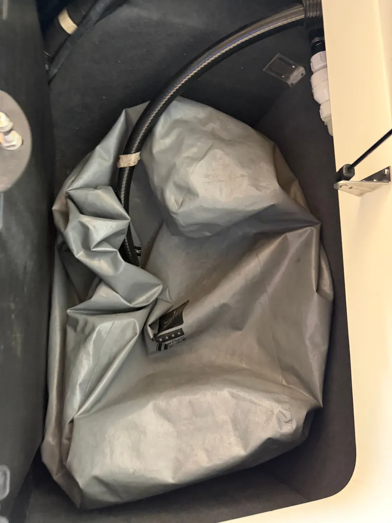 Slide: The Image of A gray ballast bag in a boat's storage compartment, surrounded by hoses and fittings. - 15