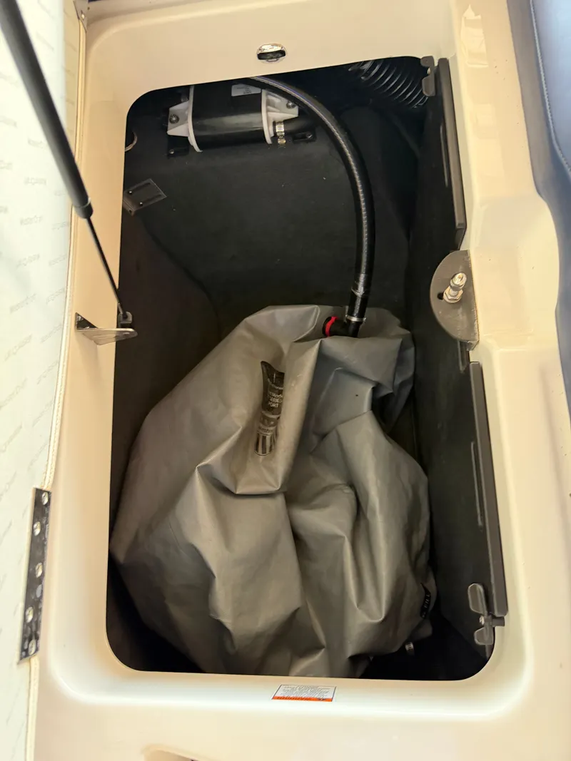 Slide: The Image of A storage compartment in the boat with a gray bag and a hose. - 14