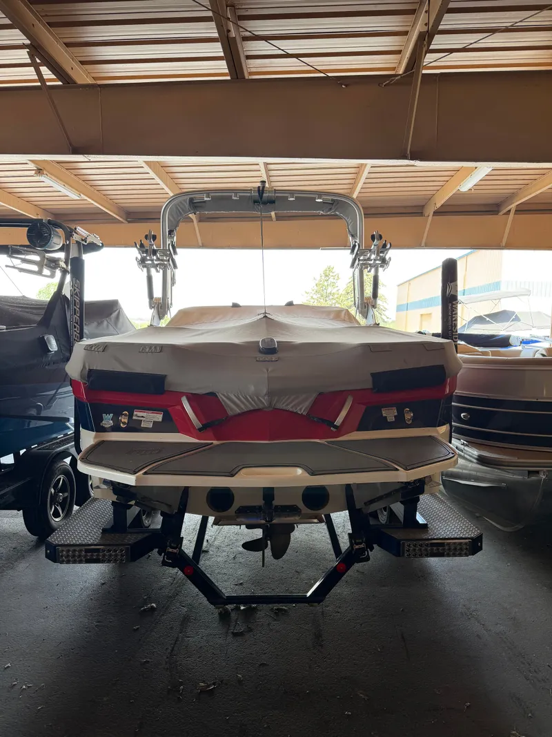 Slide: The Image of Rear view of a 2018 MasterCraft XT23 in a storage facility, with cover and trailer. - 1