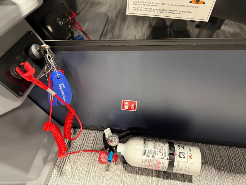 Slide: The Image of A fire extinguisher lies on the boat floor next to a keychain with a red cord. - 12