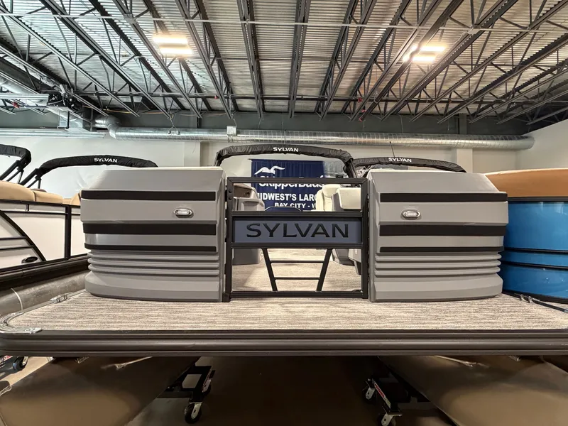 Slide: The Image of The image shows a Sylvan R-22 LZ DH pontoon boat in a showroom. - 1