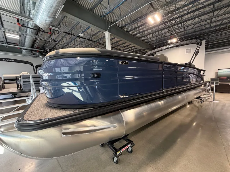 The Image of A modern pontoon boat by Sylvan, model X5 DLZ DH BAR, year 2027, displayed indoors. - 0