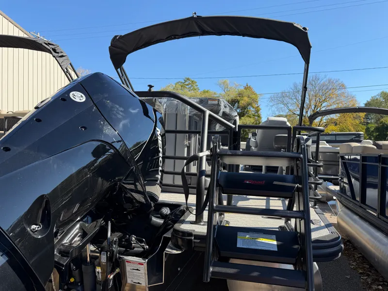 Slide: The Image of Sylvan X5 DLZ DH BAR 2027 with black outboard motor and Bimini top, parked outdoors. - 3