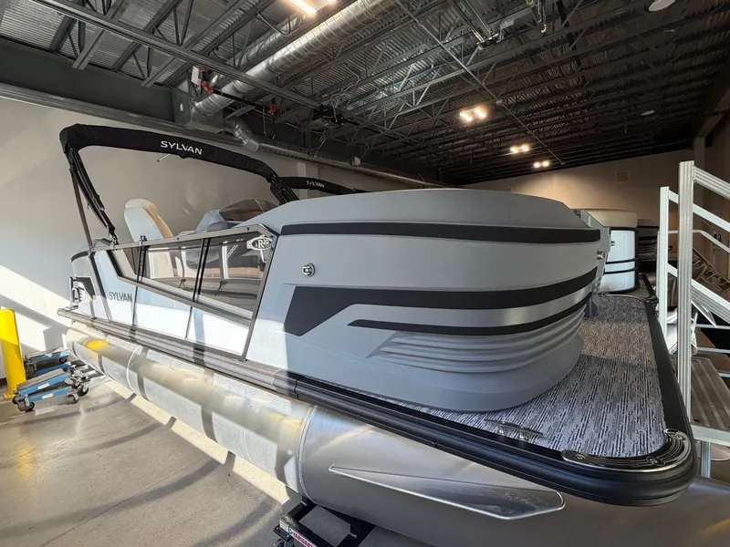 The Image of The image shows a modern Sylvan pontoon boat, model R-20 CLZ DH, inside a warehouse. - 0
