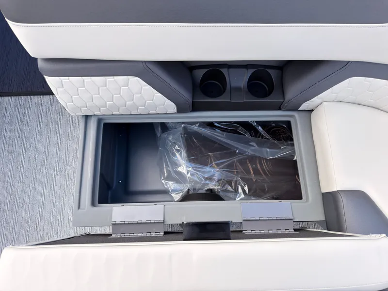 Slide: The Image of An open storage compartment on a 2027 Sylvan Q-20 Party Fish boat, featuring cup holders. - 18