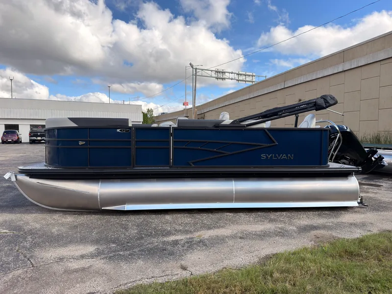 Slide: The Image of A 2027 Sylvan Q-20 Party Fish pontoon boat is parked. It features blue railings and silver pontoons. - 4