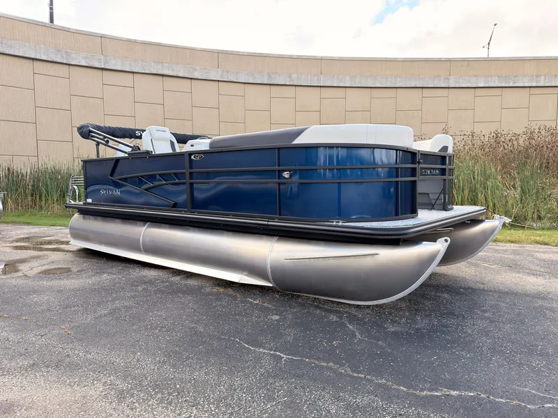 Slide: The Image of A modern pontoon boat with a blue hull and silver pontoons, parked on a paved lot. - 8