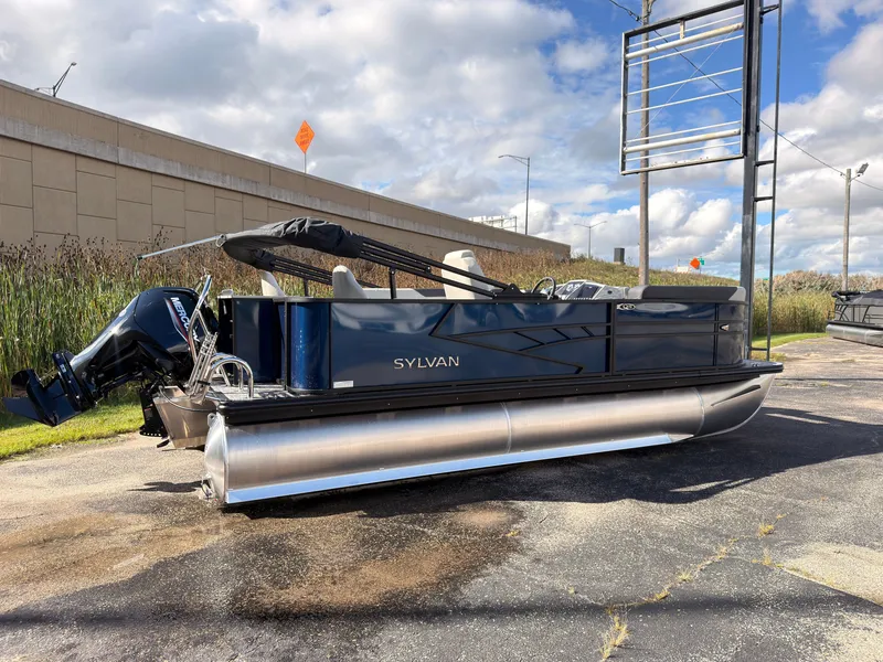 Slide: The Image of A 2027 Sylvan Q-20 Party Fish pontoon boat is parked on a lot. It features an outboard motor and a black canopy. - 1