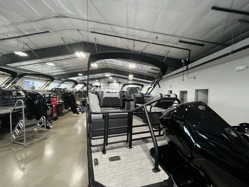 Slide: The Image of The image shows a modern pontoon boat in a warehouse. It features black seating and a canopy. - 22