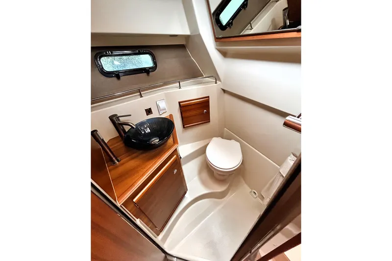 Slide: The Image of 2022 Ranger Tugs R-27 boat bathroom with modern sink, toilet, and wooden cabinetry. - 9