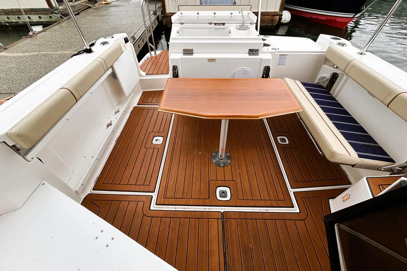 Slide: The Image of 2022 Ranger Tugs R-27 boat deck with wooden flooring and seating area. - 3