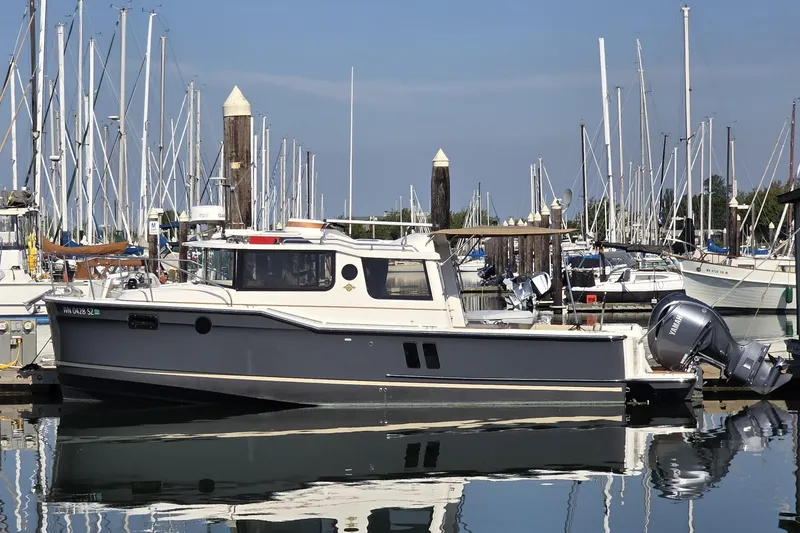 The Image of 2022 Ranger Tugs R-27 boat docked in a marina with sailboats in the background. - 0