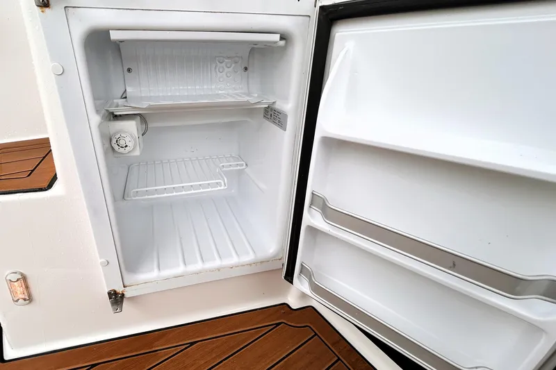 Slide: The Image of Open refrigerator on 2022 Ranger Tugs R-27 boat, showcasing interior shelves and door storage. - 18