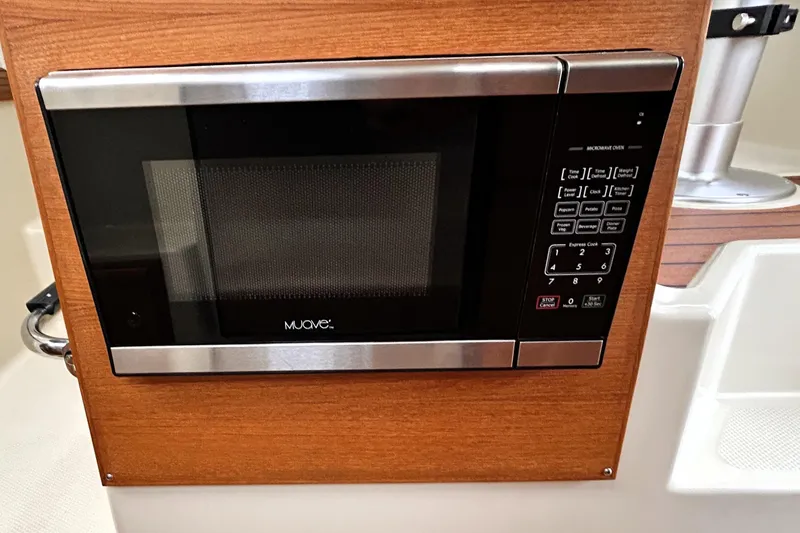 Slide: The Image of Microwave oven in 2022 Ranger Tugs R-27 boat interior, featuring wood paneling. - 17