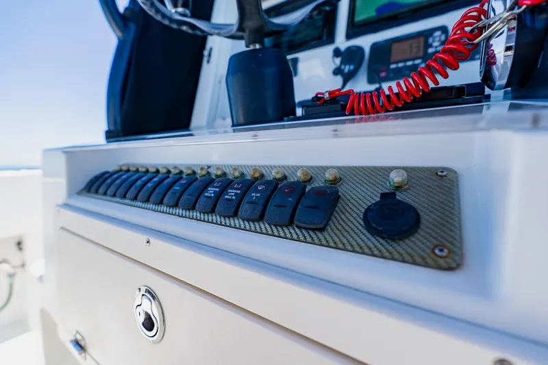 Slide: The Image of Control panel of a 2016 Andros 32 Offshore boat with switches and red coiled cord. - 51
