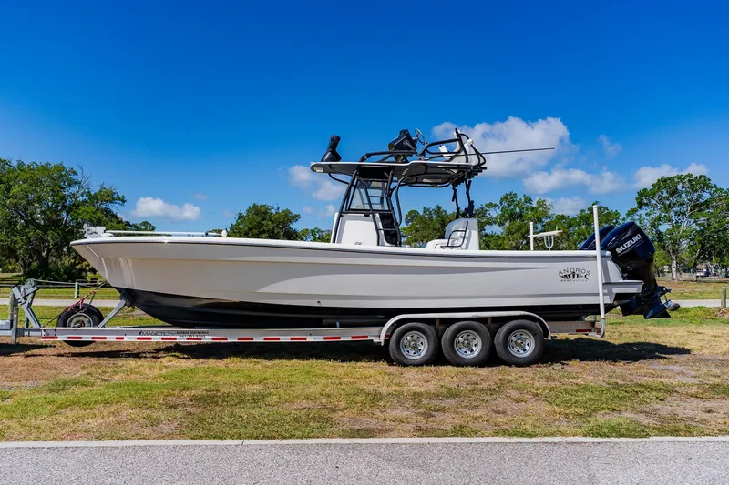 Slide: The Image of 2016 Andros 32 Offshore boat on trailer, parked on grass under clear blue sky. - 0