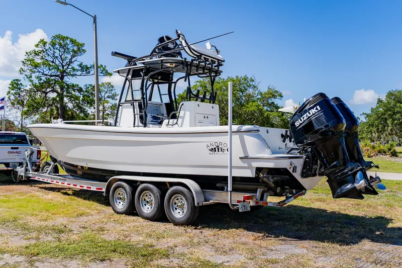 Slide: The Image of 2016 Andros 32 Offshore boat on trailer with Suzuki engines, parked outdoors. - 1