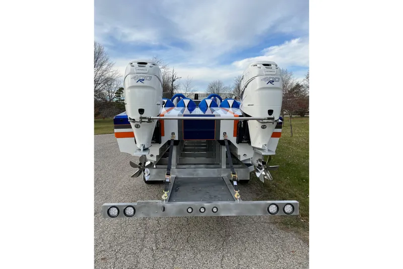 Slide: The Image of 2023 Skater 318 boat with dual outboard engines on a trailer, parked on a paved road. - 12