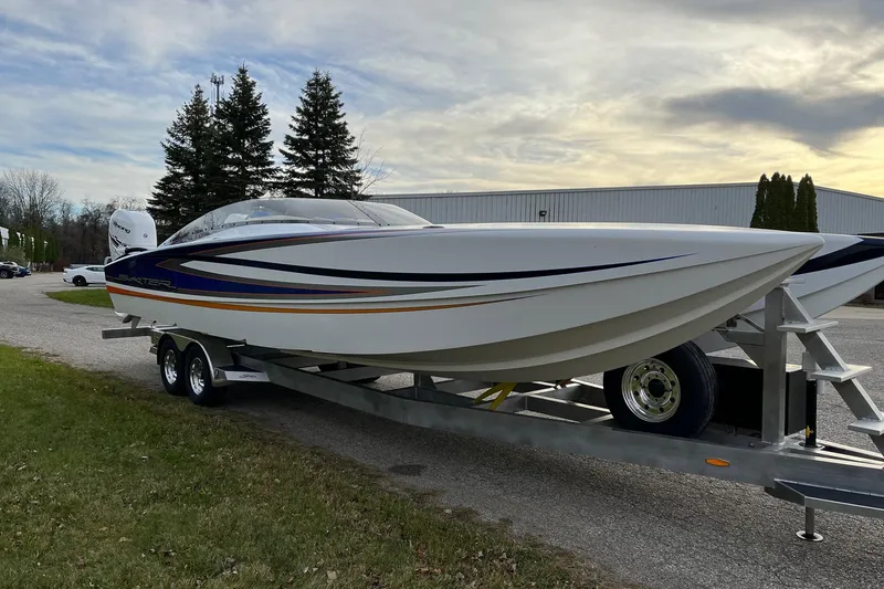 Slide: The Image of 2023 Skater 318 boat on trailer, sleek design, parked outdoors near trees and building. - 10