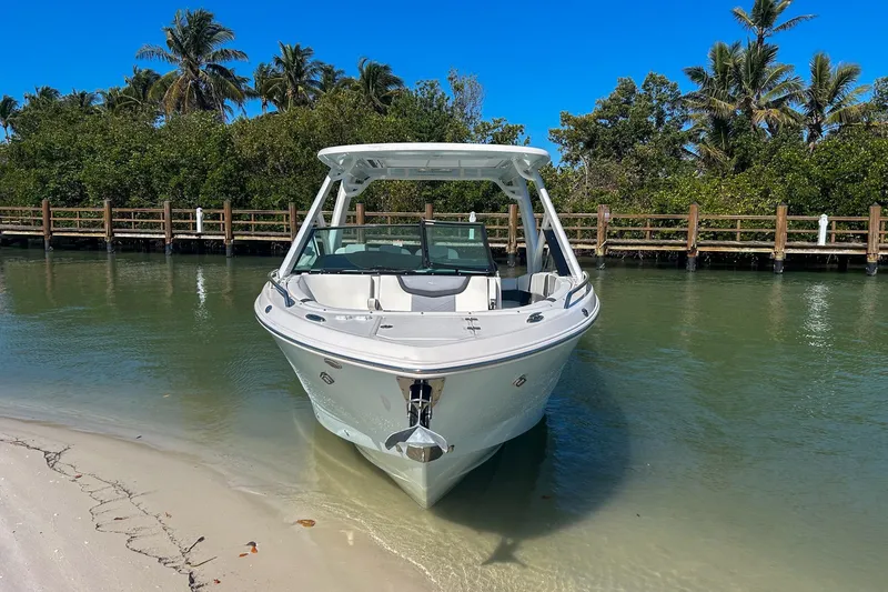 Slide: The Image of 2024 Chaparral 280 OSX boat docked on a sunny tropical shoreline. - 2