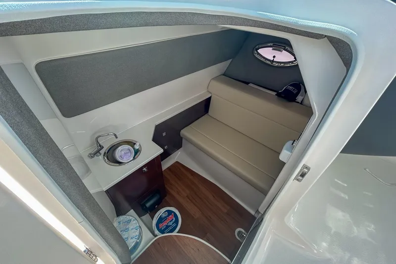 Slide: The Image of 2024 Chaparral 280 OSX cabin interior with seating, sink, and porthole window. - 16