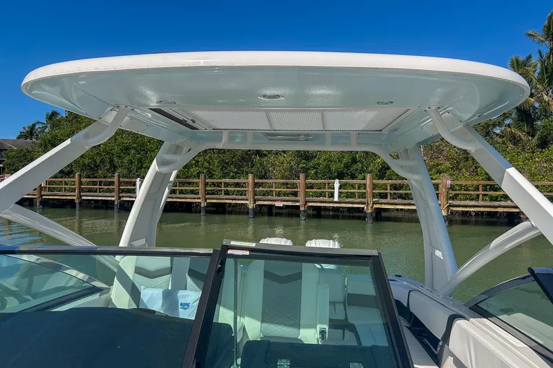 Slide: The Image of 2024 Chaparral 280 OSX boat with sleek hardtop and windshield, docked by a wooden pier. - 8