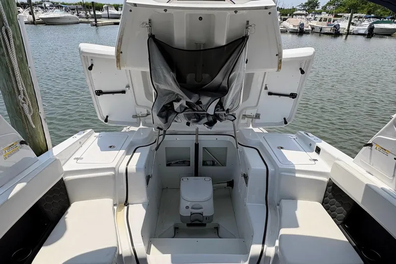 Slide: The Image of 2022 Four Winns H4 OB boat interior with open storage compartments at a marina. - 18
