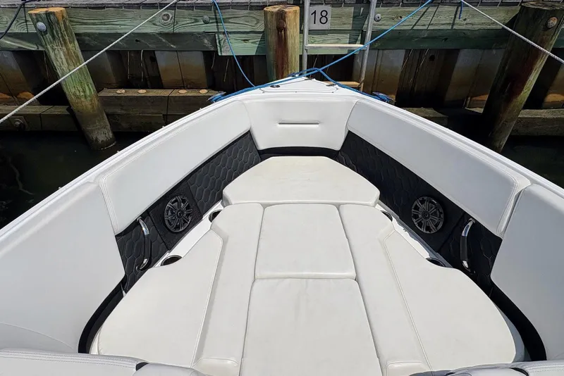 Slide: The Image of 2022 Four Winns H4 OB boat interior with white seating and speakers, docked at a wooden pier. - 4