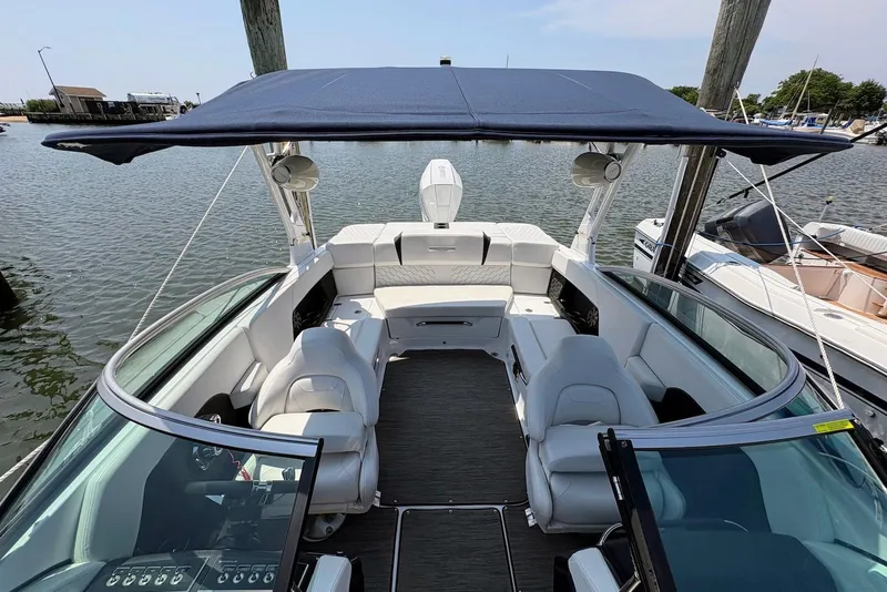 Slide: The Image of 2022 Four Winns H4 OB boat with spacious seating and canopy docked by the water. - 9
