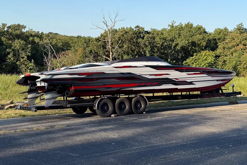 Slide: The Image of 2024 Skater 368 powerboat on trailer, featuring sleek red and black design, parked outdoors. - 51