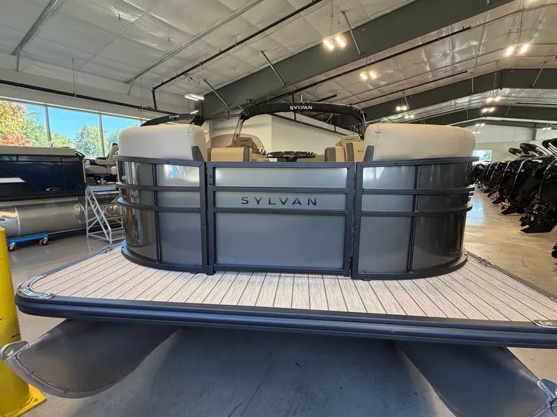 Slide: The Image of A 2027 Sylvan Q-22 ULZ pontoon boat in a showroom, featuring sleek gray paneling. - 1