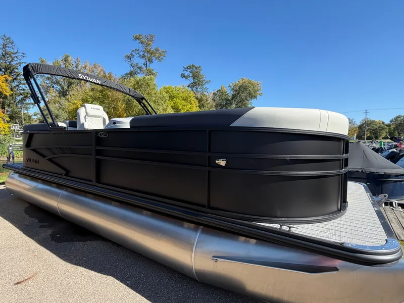 The Image of A 2027 Sylvan Q-22 LZ pontoon boat with a black hull and beige interior, on a trailer. - 0