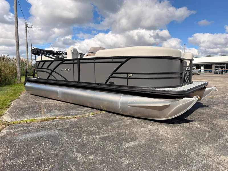 Slide: The Image of The image shows a Sylvan Mirage 822 LZ pontoon boat on a parking lot under a cloudy sky. - 8