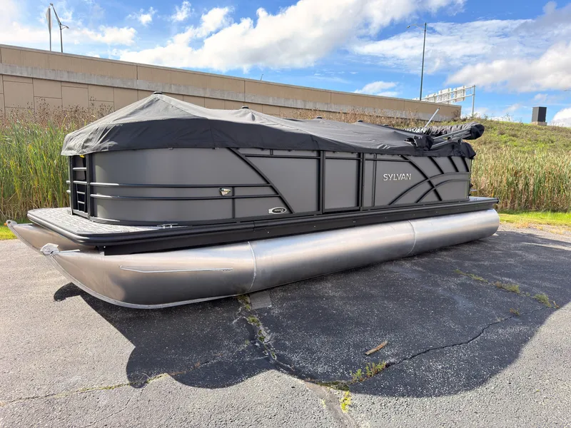 The Image of A 2027 Sylvan Mirage 822 LZ pontoon boat is parked on a lot, covered with a black tarp. - 0