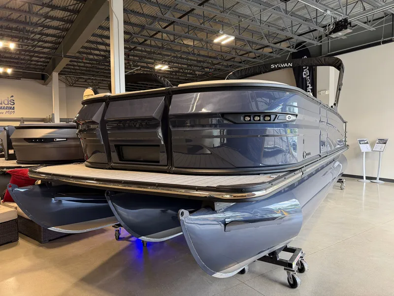 Slide: The Image of A 2027 Sylvan G-3 ULZ pontoon boat in a showroom. It features a sleek, glossy hull. - 1