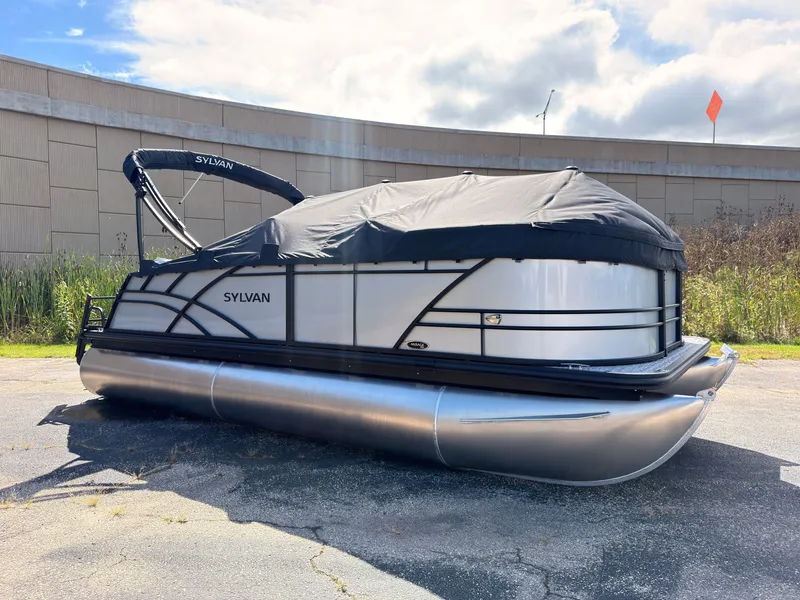 The Image of A 2027 Sylvan Mirage 820 CLZ DH pontoon boat with a black cover is parked on pavement. - 0