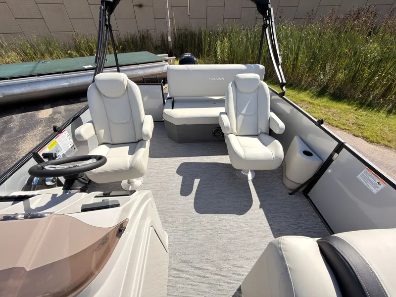 Slide: The Image of The image shows the interior of a Sylvan Mirage 820 CLZ DH boat with beige seats and a steering wheel. - 26
