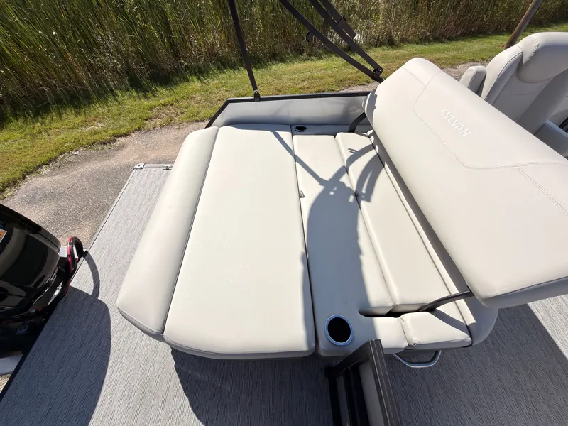 Slide: The Image of The image shows the light-colored, cushioned aft deck of a Sylvan Mirage 820 CLZ DH boat. - 45