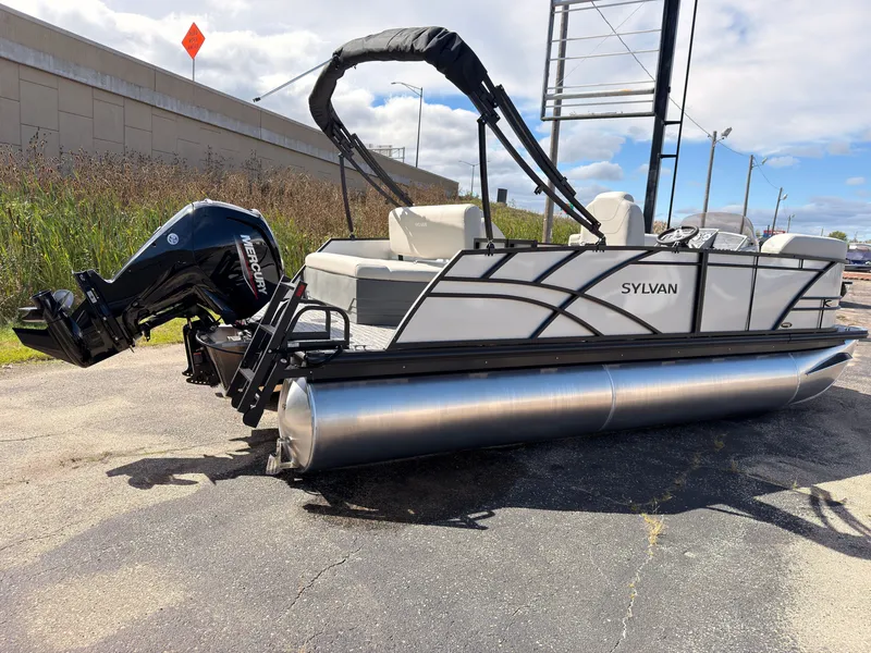 Slide: The Image of A 2027 Sylvan Mirage 820 CLZ DH pontoon boat with an outboard motor, parked on an asphalt lot. - 4